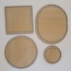 May include: Four wooden loom knitting boards in different sizes and shapes. The boards are light brown with a natural wood grain finish. The boards have a circle of holes around the edges.