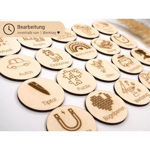Può includere: Una collezione di dischi rotondi in legno con illustrazioni incise al laser ed etichette in tedesco come Autos, Einhörner, Puzzle e Werkzeug. Ogni disco mostra un'icona unica che rappresenta vari giocattoli e oggetti per la casa.