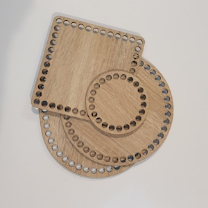 Könnte beinhalten: Drei hölzerne Strickbretter in verschiedenen Größen und Formen. Das größte Brett ist rund, das mittlere Brett ist quadratisch und das kleinste Brett ist rund. Alle drei Bretter haben Löcher an den Rändern.