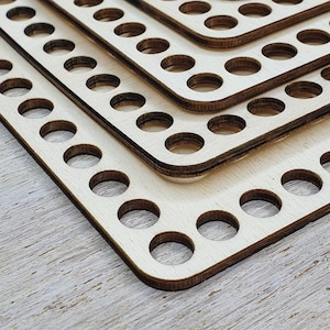 Può includere: Tre pannelli di legno con fori per chiodi di diverse dimensioni, impilati uno sopra l'altro. I pannelli sono di colore legno chiaro e sono realizzati in legno liscio e lucido. I pannelli hanno fori equidistanti per i chiodi.