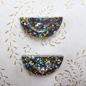 May include: Two colorful half-circle ceramic buttons with a speckled pattern in shades of red, blue, green, yellow, white, and black.