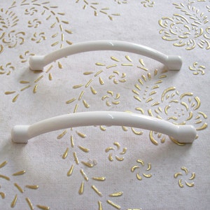 以下が含まれることがあります： 湾曲した形状の白いプラスチック製のキャビネットドアハンドル2個