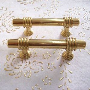 Peut inclure: Deux poignées de porte de placard dorées avec un design décoratif à nervures. Les poignées mesurent environ 10 cm de long.