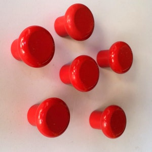 May include: Six red round cabinet knobs with a smooth finish.