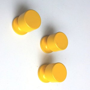 May include: Three yellow round cabinet knobs with a smooth finish.