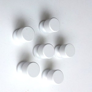 Może przedstawiać: Sześć białych plastikowych gałek z gładką, zaokrągloną powierzchnią. Gałki są ułożone w sposób przesunięty na białym tle.