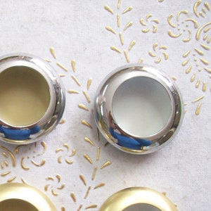 Peut inclure: Six poignées de tiroir rondes en métal avec différentes finitions. Les poignées sont chromées, dorées et noires.