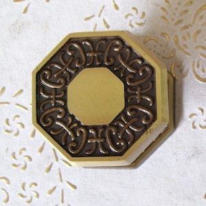 May include: Two octagonal brass knobs with a decorative, intricate design. The knobs are a dark brown colour with a gold finish.