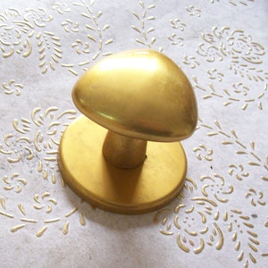 May include: A gold-colored door knob with a round base. The knob is heart-shaped and has a smooth, shiny finish.