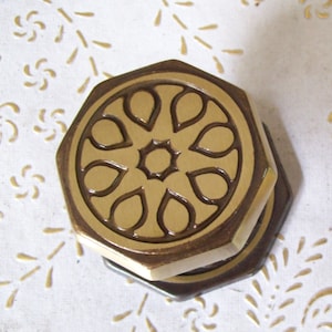 May include: Two octagonal brass door knobs with a decorative, intricate, floral design. The knobs are a dark brown colour with a gold finish.
