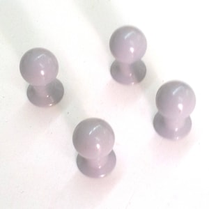 Puede incluir: Cuatro pequeños pomos redondos de plástico gris con base plana.