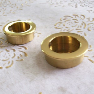 Peut inclure: Deux bougeoirs en métal de couleur dorée de tailles différentes. Le plus grand bougeoir est au premier plan et le plus petit est à l'arrière-plan.