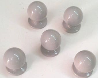 May include: Five gray ceramic cabinet knobs with a round shape and a slightly raised base.