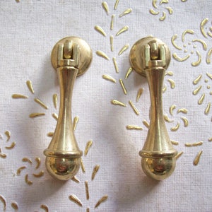 May include: Two gold-toned door knobs with a round ball at the bottom and a decorative ring at the top.