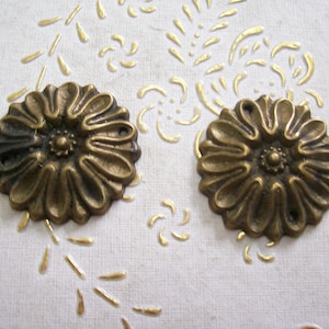 Peut inclure: Deux embellissements en métal de couleur or en forme de fleur avec un détail central en relief. Les embellissements ont une surface légèrement texturée et sont parfaits pour ajouter une touche de charme vintage aux projets d'artisanat et de décoration intérieure.