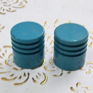 May include: Two teal blue round knobs with three raised lines around the middle.