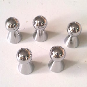 May include: Five silver-toned metal knobs with a round top and a cone-shaped base.
