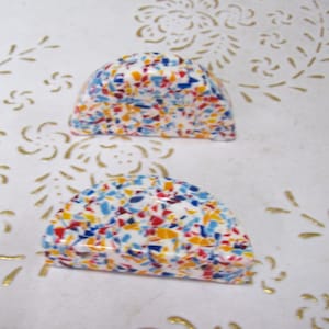 Può includere: Due pomelli in ceramica a forma di semicupola con base bianca e un motivo a coriandoli colorati in rosso, blu e giallo.