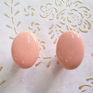 May include: Two round, pale pink, ceramic drawer knobs.