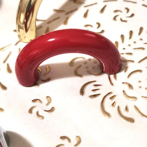 May include: A red, rounded cabinet knob with a shiny, glossy finish.