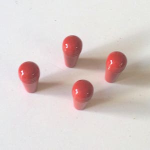 Może przedstawiać: Cztery czerwone plastikowe gałki z zaokrąglonym wierzchołkiem i fakturowaną powierzchnią.