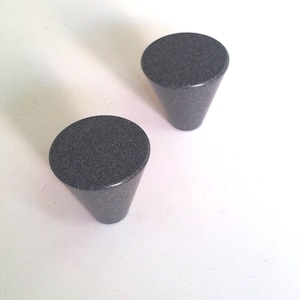 May include: Two gray cone-shaped cabinet knobs with a speckled finish.