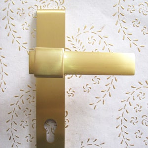 May include: A gold door handle with a keyhole. The handle is made of metal and has a brushed finish.