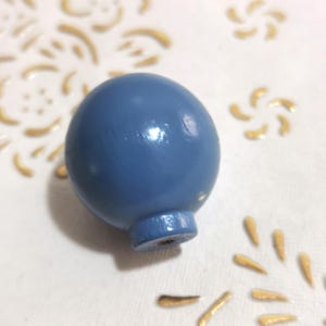 May include: A blue wooden knob with a rounded top and a small, round base.