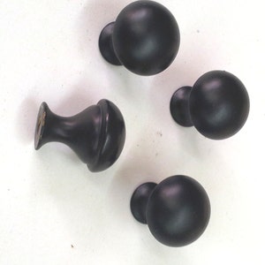 May include: Four black round cabinet knobs with a smooth finish. The knobs have a round base and a round top.