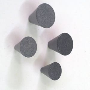 Pode incluir: Quatro botões de armário em forma de cone cinza com uma superfície texturizada.