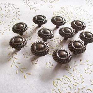 May include: A set of 12 antique bronze cabinet knobs with a decorative rope design. The knobs are round and have a raised centre.