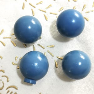 May include: Four blue round knobs with a smooth, glossy finish. The knobs are arranged in a semi-circle on a white surface with a gold pattern.