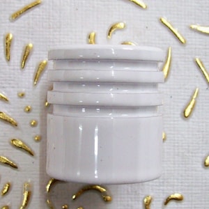 May include: White plastic bottle stopper with three raised rings around the top.