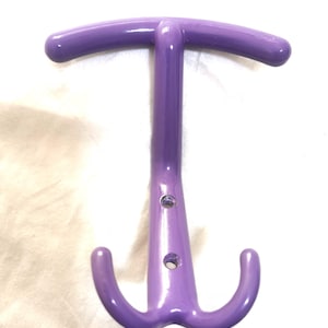 May include: A purple coat rack with a T-shaped design. The top bar is curved, and the bottom has two curved hooks. The rack has a glossy finish and two holes for mounting.