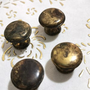 Può includere: Quattro pomelli per armadi in ottone antico con una finitura usurata e invecchiata. I pomelli hanno una parte superiore rotonda e una base cilindrica corta.