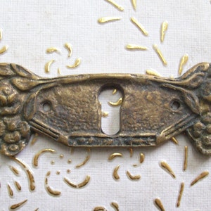 Peut inclure: Un cache-trou de serrure en laiton avec un motif floral. Le cache-trou a deux accents floraux décoratifs de chaque côté du trou de serrure.