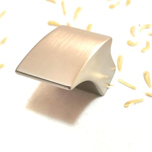 May include: A brushed nickel cabinet knob with a curved, rectangular shape.