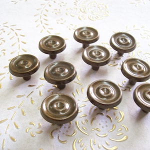 Op de afbeelding: Een set van tien bruine keramische kastknoppen met een verhoogd cirkelvormig ontwerp. De knoppen hebben een gladde, matte afwerking.