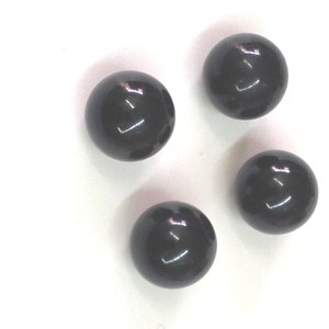 Puede incluir: Cuatro canicas redondas, lisas y brillantes de color negro.