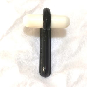 Peut inclure: Un marteau à réflexes médical noir et blanc. Le marteau a une poignée noire et une tête arrondie blanche. Un anneau noir relie la poignée à la tête. Le marteau est conçu pour les examens médicaux.