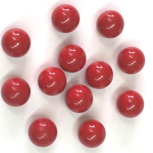 Può includere: Un gruppo di 12 perline rotonde rosse, sparse su una superficie bianca.