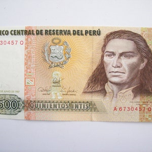 Può includere: Una banconota da 500 Intis del Perù, con il ritratto di un uomo con i capelli lunghi su uno sfondo marrone e bianco. Il testo "BANCO CENTRAL DE RESERVA DEL PERÚ" è stampato nella parte superiore della banconota. Il numero di serie "A 6730457 0" è stampato sui lati sinistro e destro della banconota.