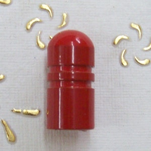 Peut inclure: Un bouchon de bouteille rouge avec un dessus lisse et arrondi et une bande texturée autour du milieu.