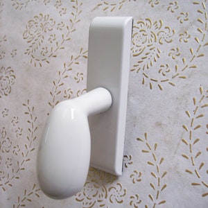 Könnte beinhalten: Weißer Türgriff mit einem abgerundeten Hebel. Der Griff ist auf einer weißen Platte montiert.