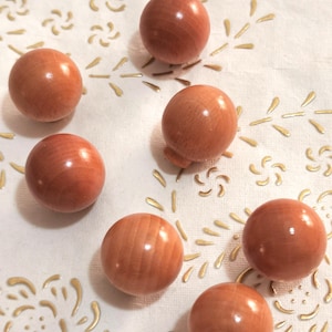 Puede incluir: Siete esferas de madera de color marrón claro. Las esferas son lisas y tienen una veta de madera natural.