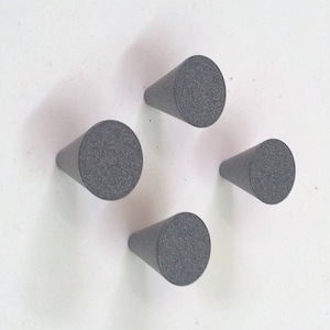 May include: Four grey, cone-shaped wall hooks arranged in a cluster. The hooks are made of a textured material and are mounted on a white surface. Each hook has a diameter of approximately 3.8 cm.