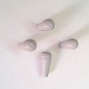 Peut inclure: Cinq boutons en plastique blanc, quatre sont ronds et un est cylindrique avec des crêtes.