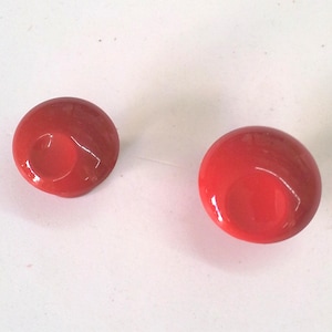 Peut inclure: Deux boutons ronds rouges avec un centre légèrement surélevé. Les boutons sont lisses et brillants.