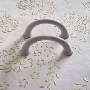 May include: Two gray metal cabinet door pulls with a rounded arch shape.