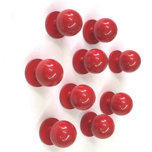 May include: Ten red round cabinet knobs with a shiny finish.